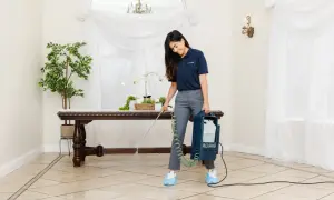 A woman uses a multi-sprayer for polished porcelain tile cleaner, ensuring a spotless shine in a well-lit room with elegant decor.