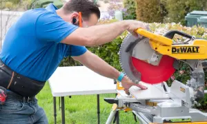 Man using a miter saw to cut SmartCore flooring. He's wearing safety glasses and ear protection.