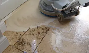 A floor buffer machine is used to clean travertine tile, creating suds and removing dirt.