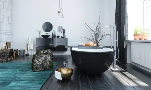 Modern bathroom with a black freestanding tub, dark wood floors, and a teal rug.