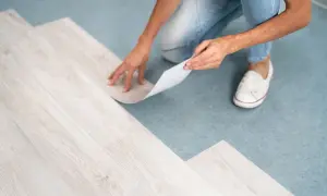 A person is installing vinyl plank flooring, but one plank isn't laying flat.