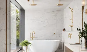 A luxurious bathroom featuring white marble tile with light grey grout, a freestanding tub, and gold fixtures.