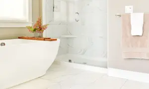 A modern bathroom with white marble tiles and a subtle marble tile grout color. A freestanding tub and glass shower create a spa-like feel.