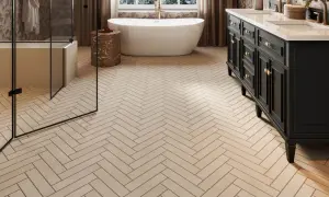 Herringbone floor tiles, likely ceramic or porcelain, create a warm, natural look in this modern bathroom with a freestanding tub and dark vanity.
