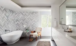 A luxurious bathroom features a freestanding tub and a stunning herringbone pattern shower wall.