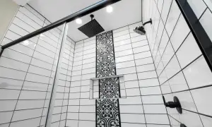 Modern shower with white subway tiles and black grout, featuring a decorative black tile accent and black fixtures.