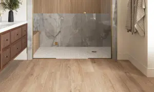 Modern bathroom with wood-look porcelain tile flooring. The shower features marble-look tile and wood accents. Considering porcelain wood tile pros and cons for your next renovation?