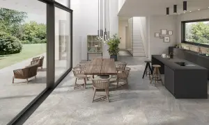 Modern dining and kitchen area with a seamless stone flooring installation, connecting indoor and outdoor spaces.