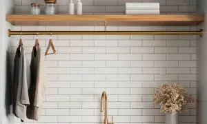 A laundry room with white tile beige grout walls, a wooden shelf, and a brass rod holding clothes.