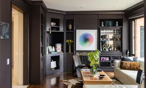 Dark floors can make a room feel cozy, not smaller. This living room features dark wood floors, a built-in bar, and a colorful art piece.