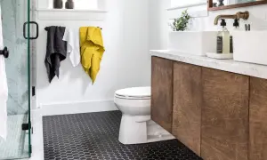 Modern bathroom with dark hexagonal tile floor, a classic choice for types of bathroom floor, a white toilet, and a wooden vanity.