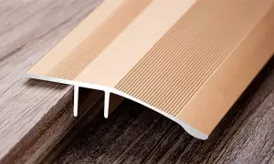 A metallic transition strip bridges two different wood-look floors, one lighter and one darker, showcasing the seamless finish of cut vinyl flooring.