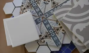 A collection of assorted tiles, including white hexagons, patterned squares, and grey wavy tiles, perfect for DIY leftover tile ideas.