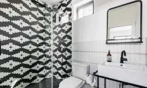 A modern bathroom with a striking black and white tile texture on the shower walls. The geometric pattern creates a bold statement.