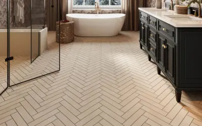 Herringbone floor tiles, likely ceramic or porcelain, create a warm, natural look in this modern bathroom with a freestanding tub and dark vanity.