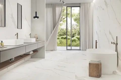 A modern bathroom with Carrara marble tiles. The best grout color for Carrara marble is subtle, allowing the natural veining to shine.