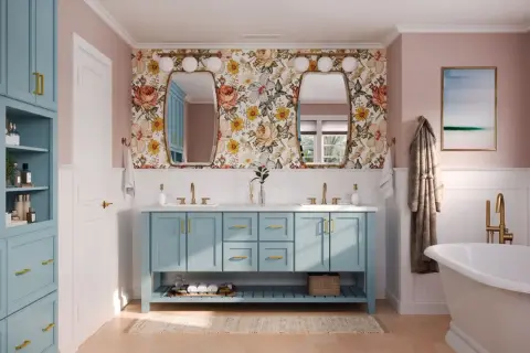 A bright bathroom with a floral wallpaper, a blue double vanity, and a freestanding tub. This blue is a beautiful choice for the best color for bathroom cabinets.