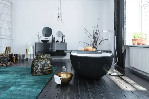 Modern bathroom with a black freestanding tub, dark wood floors, and a teal rug.