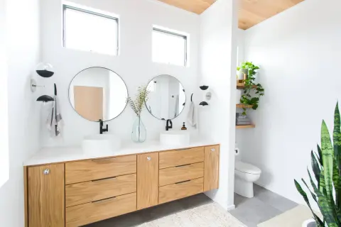 Modern bathroom with dual sinks, wooden vanity, and round mirrors. The bathroom mirror height is ideal for comfortable use.