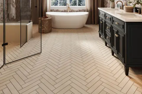 Herringbone floor tiles, likely ceramic or porcelain, create a warm, natural look in this modern bathroom with a freestanding tub and dark vanity.