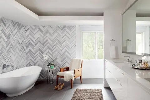 A luxurious bathroom features a freestanding tub and a stunning herringbone pattern shower wall.