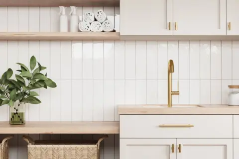 A modern laundry room with white subway tiles and subtle grout options. A gold faucet and brass hardware add a touch of luxury.