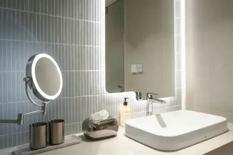 A modern bathroom vanity with a lighted makeup mirror, showcasing the best bathroom lighting for makeup.