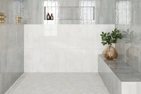 Modern shower with hexagonal subway tile on floor, marble wall, and glass shower walls.