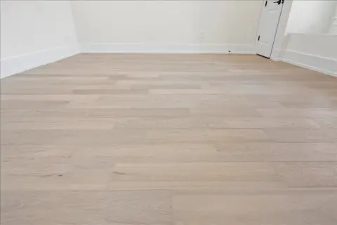 Light wood vinyl plank flooring laid in a room. This image shows the result of how to start vinyl plank flooring, with clean lines and a modern look.