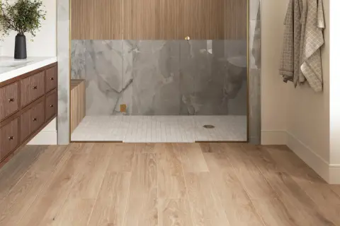 Modern bathroom with wood-look porcelain tile flooring. The shower features marble-look tile and wood accents. Considering porcelain wood tile pros and cons for your next renovation?