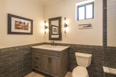 Bathroom vanity with a sink, mirror, and two wall sconces. The sconce height from floor is about 4 feet, illuminating the artwork and vanity.