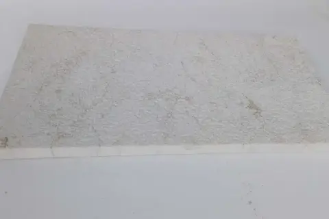 A textured, off-white limestone slab, showing some discoloration. This image could illustrate how to clean limestone.