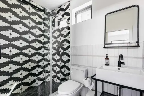 A modern bathroom with a striking black and white tile texture on the shower walls. The geometric pattern creates a bold statement.