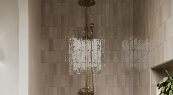 A modern shower with matte porcelain tiles and a brass showerhead. Learn how to clean matte porcelain tiles in shower spaces for a sparkling finish.