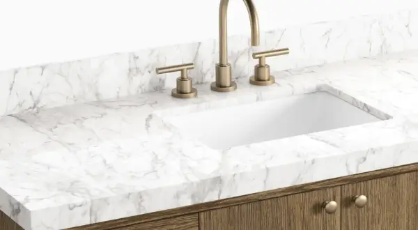 A modern bathroom vanity with a white sink, brass faucet, and a white marble countertop. This image showcases a stylish option to replace bathroom countertop.