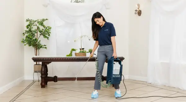 A woman uses a multi-sprayer for polished porcelain tile cleaner, ensuring a spotless shine in a well-lit room with elegant decor.