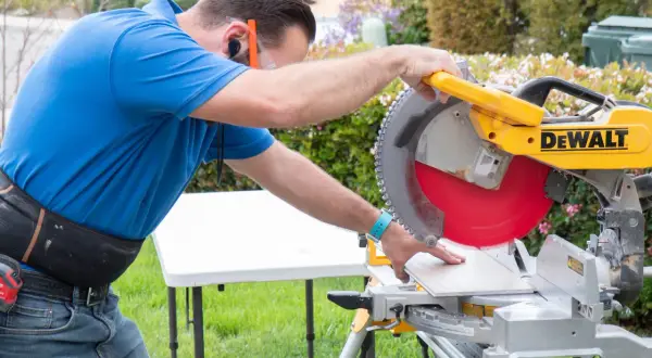 Man using a miter saw to cut SmartCore flooring. He's wearing safety glasses and ear protection.