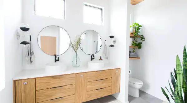Modern bathroom with dual sinks, wooden vanity, and round mirrors. The bathroom mirror height is ideal for comfortable use.