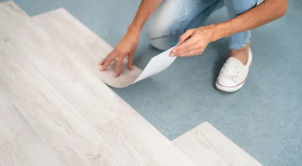 A person is installing vinyl plank flooring, but one plank isn't laying flat.