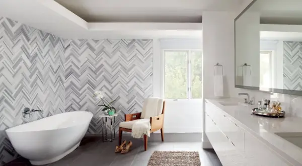 A luxurious bathroom features a freestanding tub and a stunning herringbone pattern shower wall.