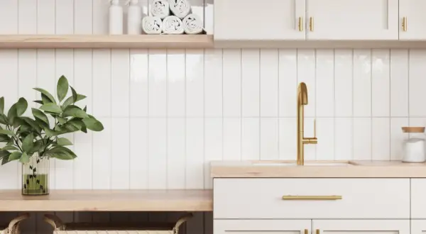 A modern laundry room with white subway tiles and subtle grout options. A gold faucet and brass hardware add a touch of luxury.