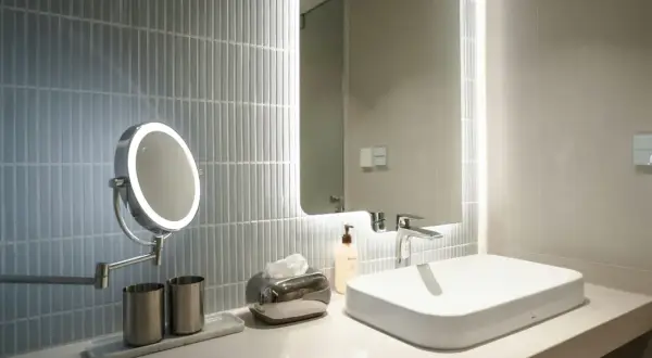 A modern bathroom vanity with a lighted makeup mirror, showcasing the best bathroom lighting for makeup.