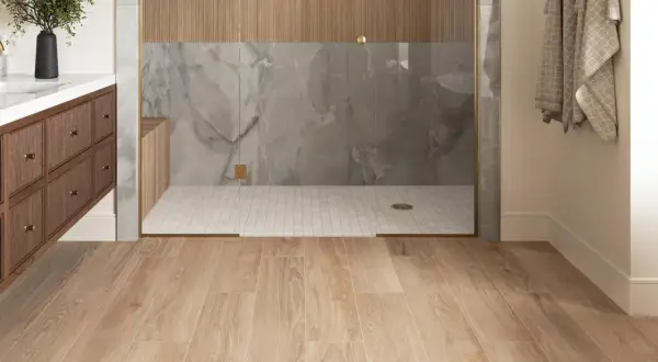 Modern bathroom with wood-look porcelain tile flooring. The shower features marble-look tile and wood accents. Considering porcelain wood tile pros and cons for your next renovation?