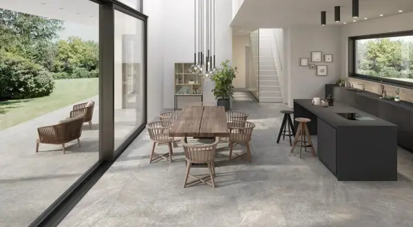 Modern dining and kitchen area with a seamless stone flooring installation, connecting indoor and outdoor spaces.