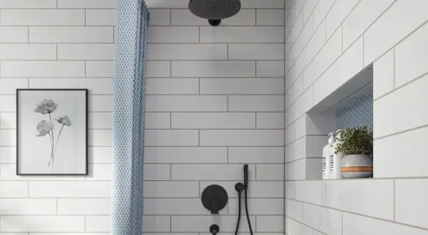 A modern bathroom features white subway tile with light gray grout, a black showerhead, and a patterned shower curtain.