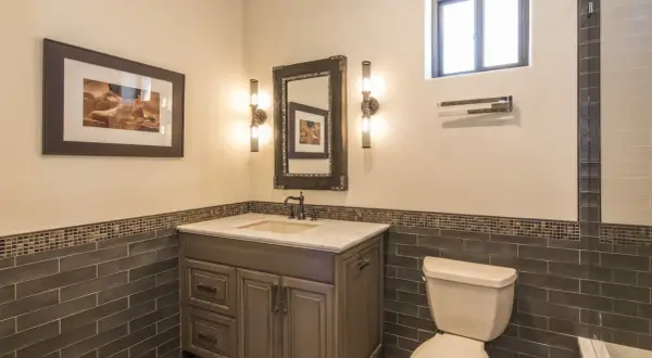 Bathroom vanity with a sink, mirror, and two wall sconces. The sconce height from floor is about 4 feet, illuminating the artwork and vanity.