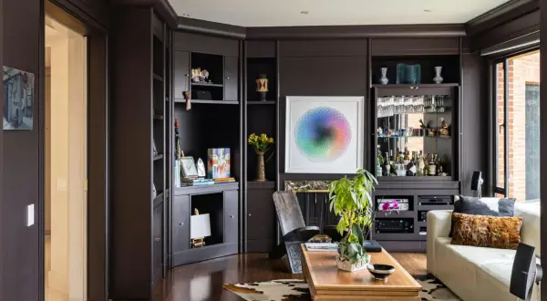 Dark floors can make a room feel cozy, not smaller. This living room features dark wood floors, a built-in bar, and a colorful art piece.