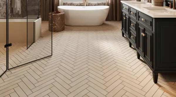 Elegant bathroom with a freestanding tub, double vanity, and glass shower, all set on beautiful natural stone flooring laid in a herringbone pattern.