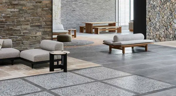 Modern living space with stone walls, wooden furniture, and a striking terrazzo design floor.
