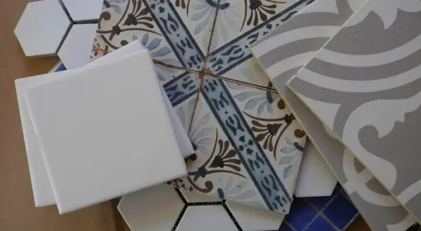 A collection of assorted tiles, including white hexagons, patterned squares, and grey wavy tiles, perfect for DIY leftover tile ideas.